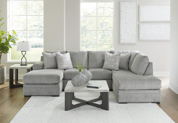 Grey plush U-shaped sectional sofa with chaise, Ashley Casselbury 2-piece design in cement fabric, shown in a living room setting.