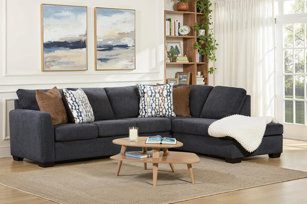 Dark blue Behold L-shaped sectional sofa with plush cushions and modern design, shown from a side angle in a living room setting.