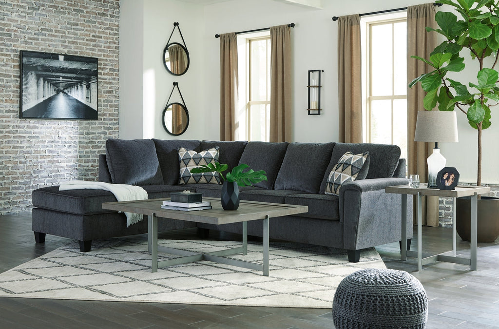 Slate grey Ashley L-shaped sectional sofa in a modern studio, showcasing plush cushions and sleek design.