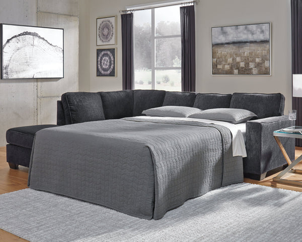 Slate grey Ashley L-shaped sleeper sectional sofa in a modern studio setting, showcasing its sleek design and spacious seating.