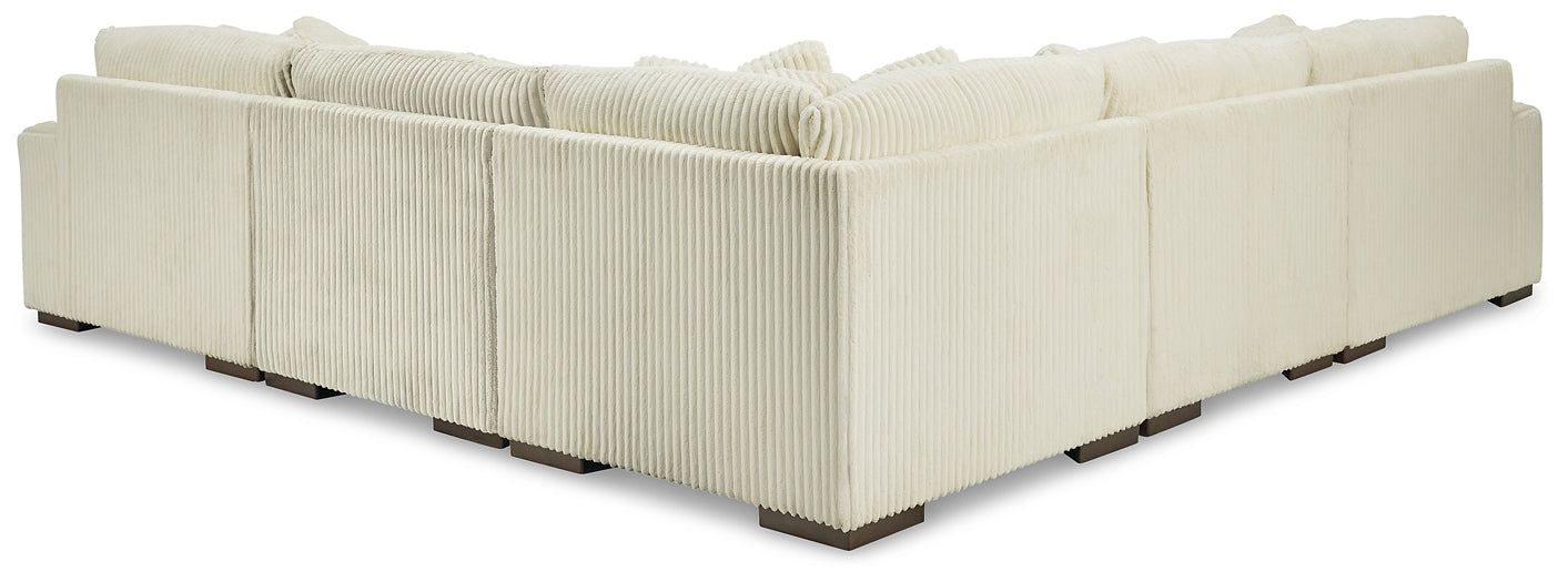 Ivory corduroy L-shaped sectional sofa by Ashley, featuring plush cushions and a modern design in a studio setting.