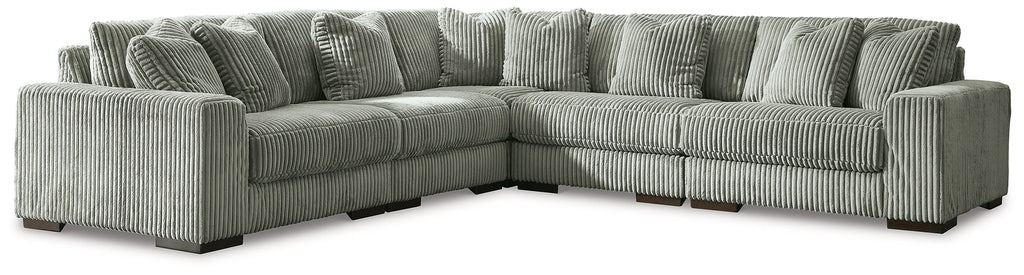 Green corduroy L-shaped sectional sofa by Ashley, shown in a modern studio setting with plush cushions and sleek design.