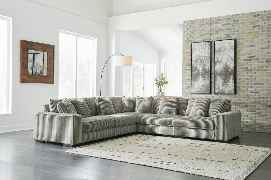 Green corduroy L-shaped sectional sofa by Ashley, shown in a modern studio setting with plush cushions and a spacious design.