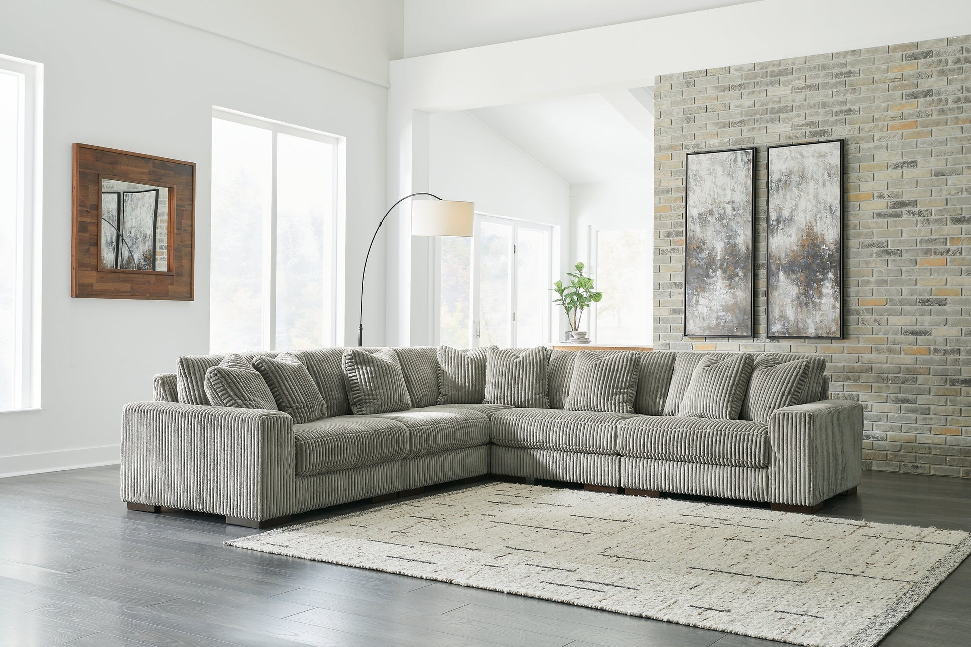 Green corduroy L-shaped sectional sofa by Ashley, shown in a modern studio setting with plush cushions and a spacious design.