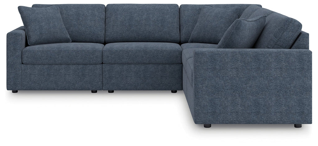 Blue Ashley modular L-shaped sectional sofa in a modern studio setting, featuring plush cushions and sleek design.