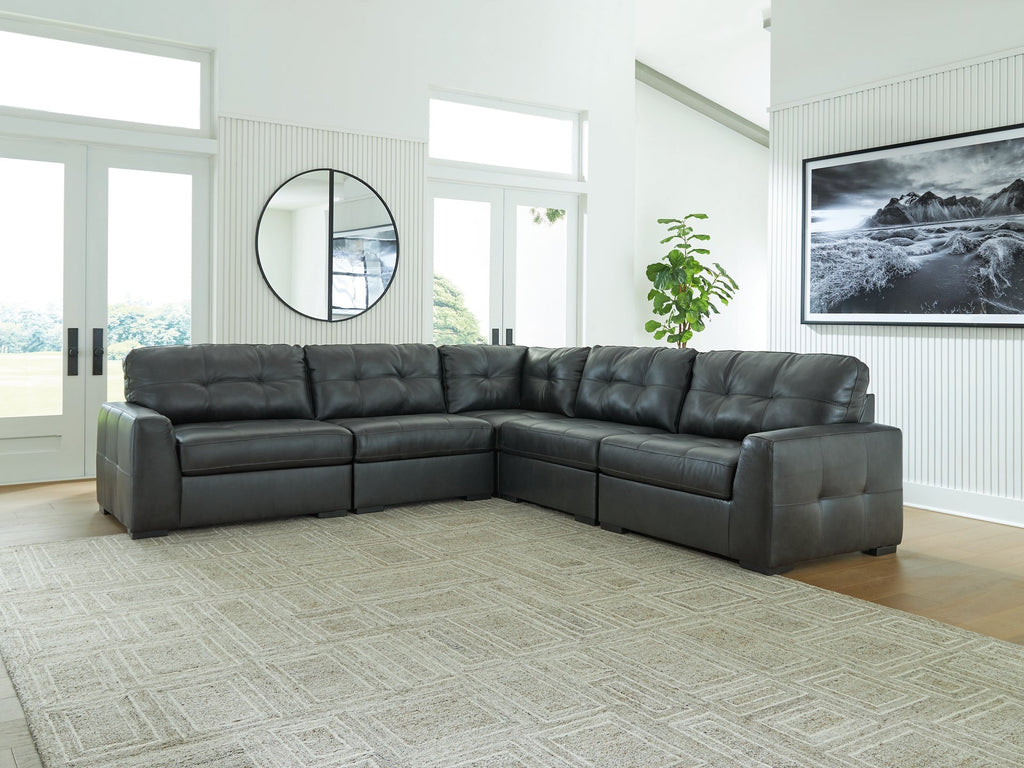 Black genuine leather L-shaped sectional sofa by Ashley, shown in a modern studio setting with plush cushions and sleek design
