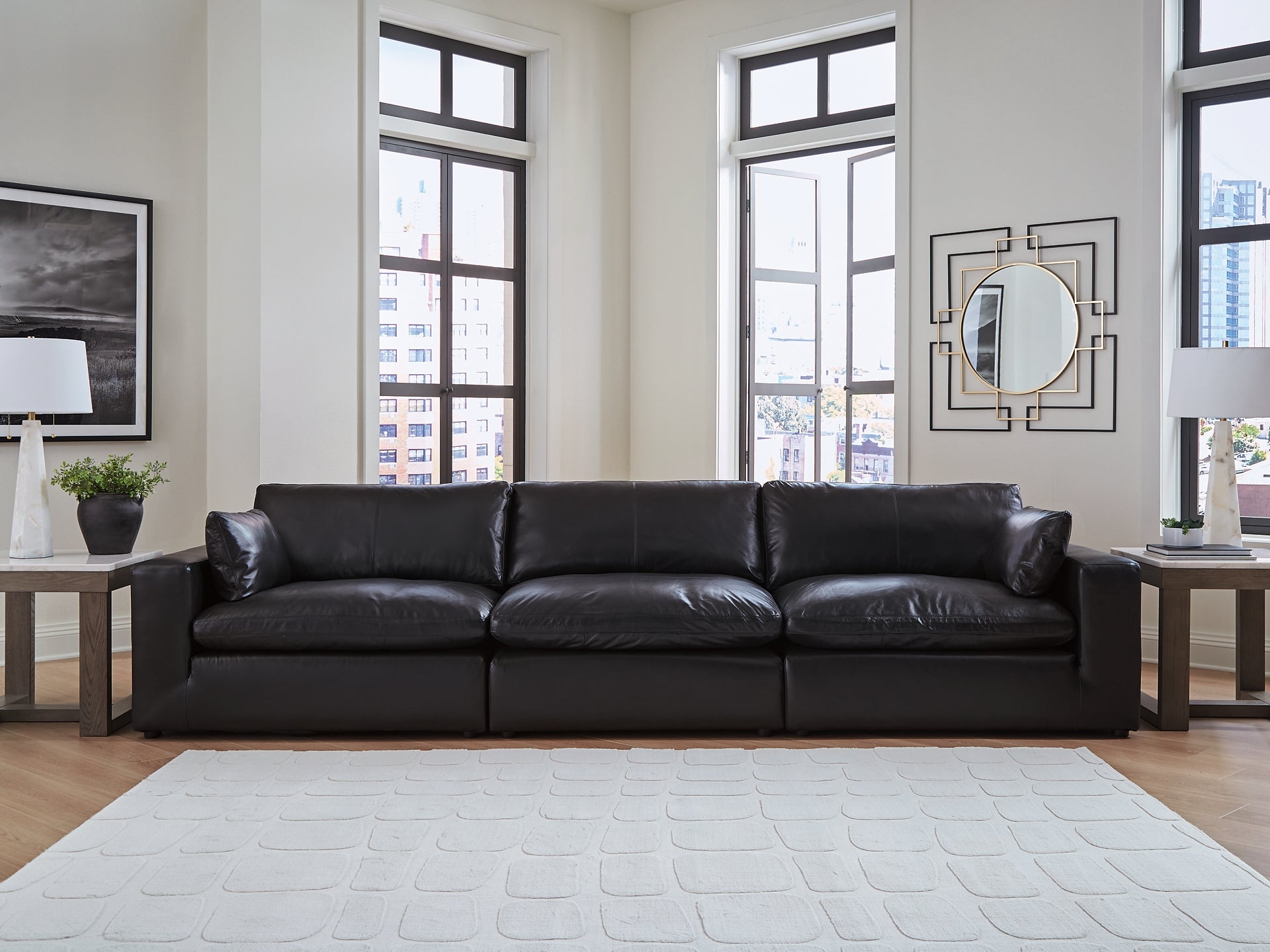 Three-piece black genuine leather sectional sofa by Ashley, shown in a modern studio setting with plush cushions and sleek design.