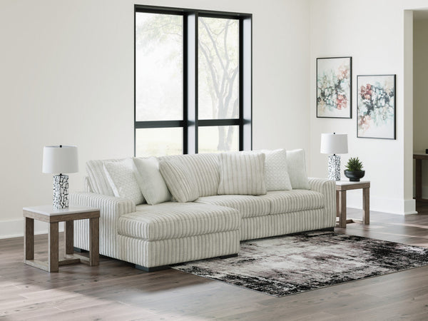 Light grey corduroy sofa chaise by Ashley with plush cushions and modern design, shown in a stylish studio setting.